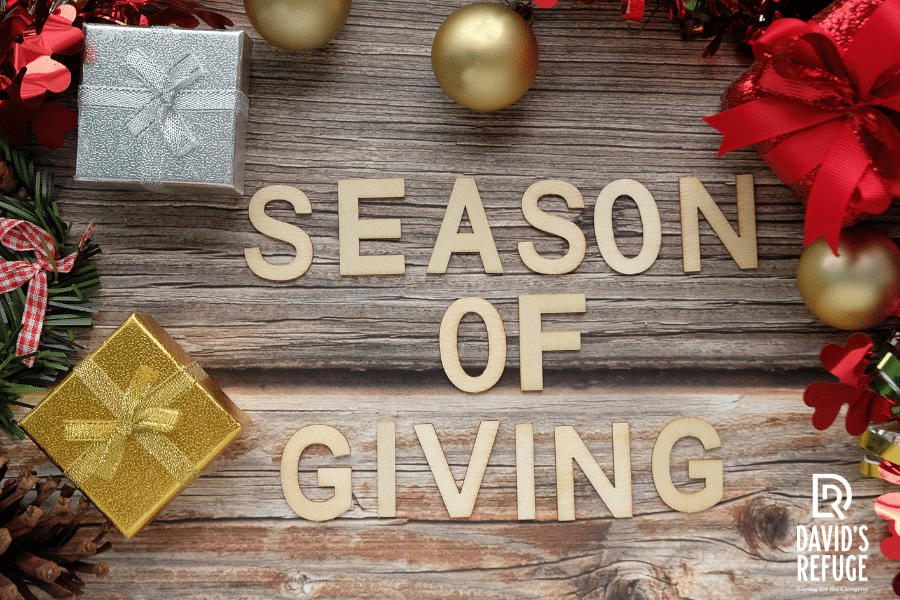 Gifts arranged on a wooden floor with block letters centered in the photo spelling out 'season of giving'